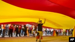 Seorang remaja berjalan di bawah bendera Spanyol raksasa di Madrid, Spanyol, Sabtu, 7 Oktober 2017.