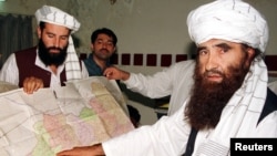 Jalaluddin Haqqani (R), the leader of the Haqqani network, points to a map of Afghanistan during a visit to Pakistan while his son looks on in this October 19, 2001 photograph. 