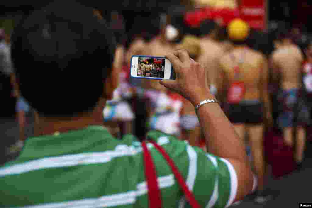 A tourist records a video of people in their underwear with his mobile phone before they enter a clothing store in Madrid. A Spanish retail clothing chain said they would give clothes to people who came in their underwear as part of a promotional publicity stunt.