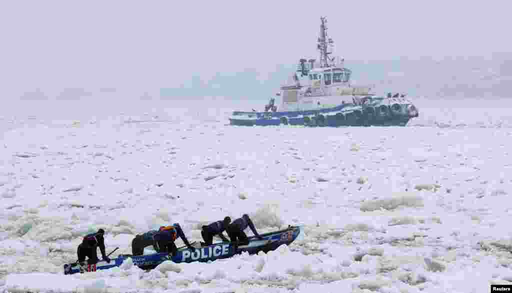 Para anggota polisi Quebec mengikuti lomba kano di atas sungai yang membeku di Quebec City, Kanada.