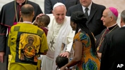 Pope Francis greets a family in the Paul VI hall at the Vatican at the end a meeting with participants in the "Evangelii Gaudium" conference organized by the Pontifical council for the new evangelization, Sept. 19, 2014. 