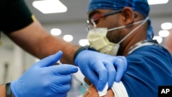 Seorang petugas kesehatan menerima suntikan booster vaksin COVID-19 Pfizer di Jackson Memorial Hospital in Miami pada 5 Oktober 2021. (Foto: AP/Lynne Sladky)