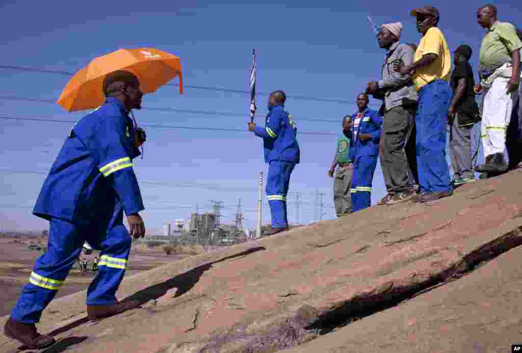 Miners who survived last year's shooting gather at the scene were they lost their fellow workers in Marikana, South Africa, August 15, 2013.