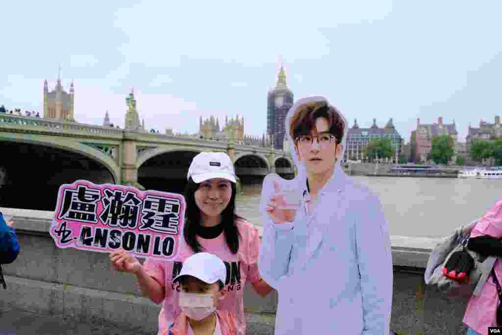 A fan poses with a full-size paperboard Anson Lo cut-out in central London, Sept. 25, 2021. (Kris Cheng/VOA Mandarin)