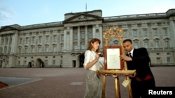 The press Secretary to Britain's Queen Elizabeth and footman Badar Azim place a notice announcing Prince George's birth.