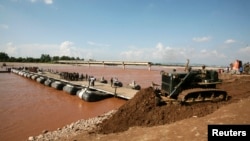 Indian Army soldiers build a temporary bridge across the river Tawi, near the existing bridge which was swept away by floodwaters from the river Tawi, Sept. 9, 2014. 