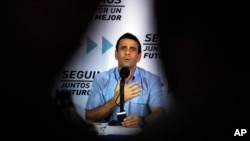 El líder de la oposición venezolana Henrique Capriles es flanqueado por las siluetas de los periodistas.