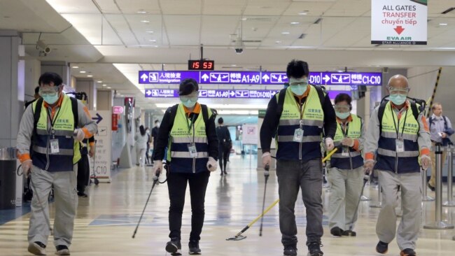 戴著口罩的工作人員在台北桃園機場噴洒消毒藥水防範新冠病毒。(2020年1月22日)