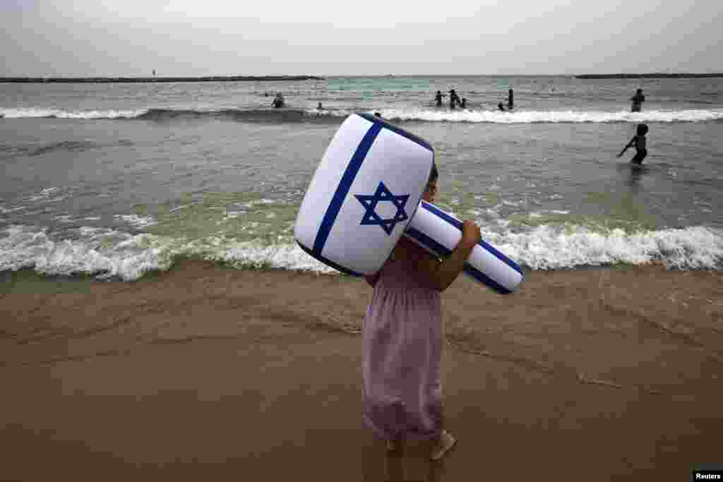 A girl holds an inflatable hammer in the color of the Israeli flag at Tel Aviv beach during Independence Day celebration. The celebration marked the 66th anniversary of the creation of Israel.