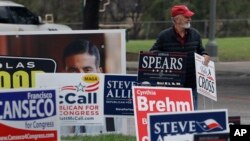 Jim Mathis looks to place a campaign sign near a polling site as early voting begins, Feb. 20, 2018, in San Antonio. Early voting in Texas runs though March 2, 2018.