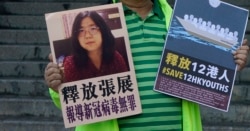 一名香港民主活动人士在中联办外手持上海维权人士、公民记者张展的照片。（2020年12月28日）