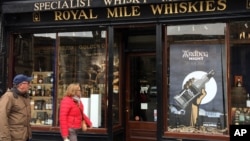In this picture taken on Saturday, May 28, 2016, a man and a woman pass a whisky shop on the “Royal mile” in Edinburgh, Scotland. Scotch Whisky Distillers, small and large, are very supportive of the UK’s membership of the European Union. Scotch Whisky is Scotland’s biggest export, supporting about 40,000 jobs in Scotland. 