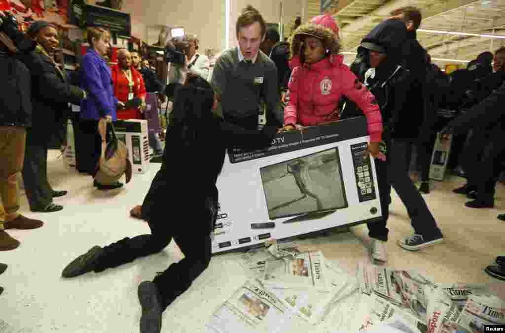 Shoppers wrestle over a television on "Black Friday" at a store in London. British stores were awash with discounts Friday as more retailers than ever embraced U.S.-style "Black Friday" promotions.
