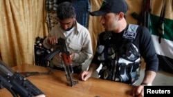 A member of the Free Syrian Army checks a weapon before buying it inside a shop in the al-Myassar neighborhood of Aleppo, May 20, 2013.