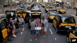 Taxi drivers block the Gran Via avenue in Barcelona, Spain, July 30, 2018. Taxi drivers in Barcelona are blocking traffic on a major thoroughfare as part of an indefinite strike to protest the use of ride-hailing apps like Uber and Cabify. 
