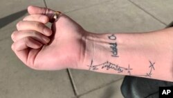 Sexual assault survivor Sam Gaspardo displays her "HOLD ON" and "to infinity" tattoos on her right arm in Minneapolis, Minnesota, Dec. 18, 2018. The "HOLD ON" tattoo is in her mother's handwriting. It's to remind Sam to hold on when she's struggling.