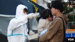 A man and a child are checked for radiation exposure in Fukushima in wake of the reactor meltdowns, March 13, 2011. (S. Herman/VOA)