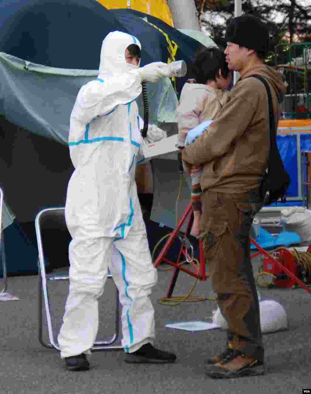 A man and a child are checked for radiation exposure in Fukushima in wake of the reactor meltdowns, March 13, 2011. (S. Herman/VOA)