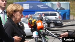 Germany's Chancellor Angela Merkel speaks near a promotional campaign bus of candidate for the European Commission presidency Jean-Claude Juncker as she arrives at an European People's Party meeting in Kortrijk, June 26, 2014.