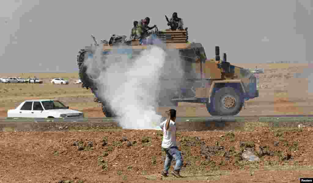 A protester throws stones at an armored army vehicle during a pro-Kurdish demonstration in solidarity with people of Kobani, near the Mursitpinar border crossing on the Turkish-Syrian border, in the Turkish town of Suruc in southeastern Sanliurfa province