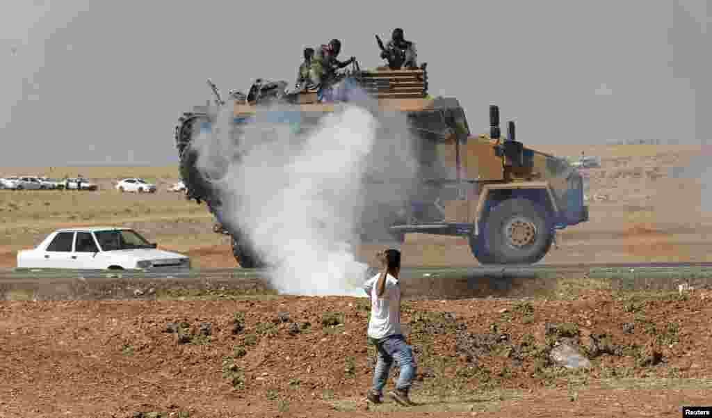 A protester throws stones at an armored army vehicle during a pro-Kurdish demonstration in solidarity with people of Kobani, near the Mursitpinar border crossing on the Turkish-Syrian border, in the Turkish town of Suruc in southeastern Sanliurfa province