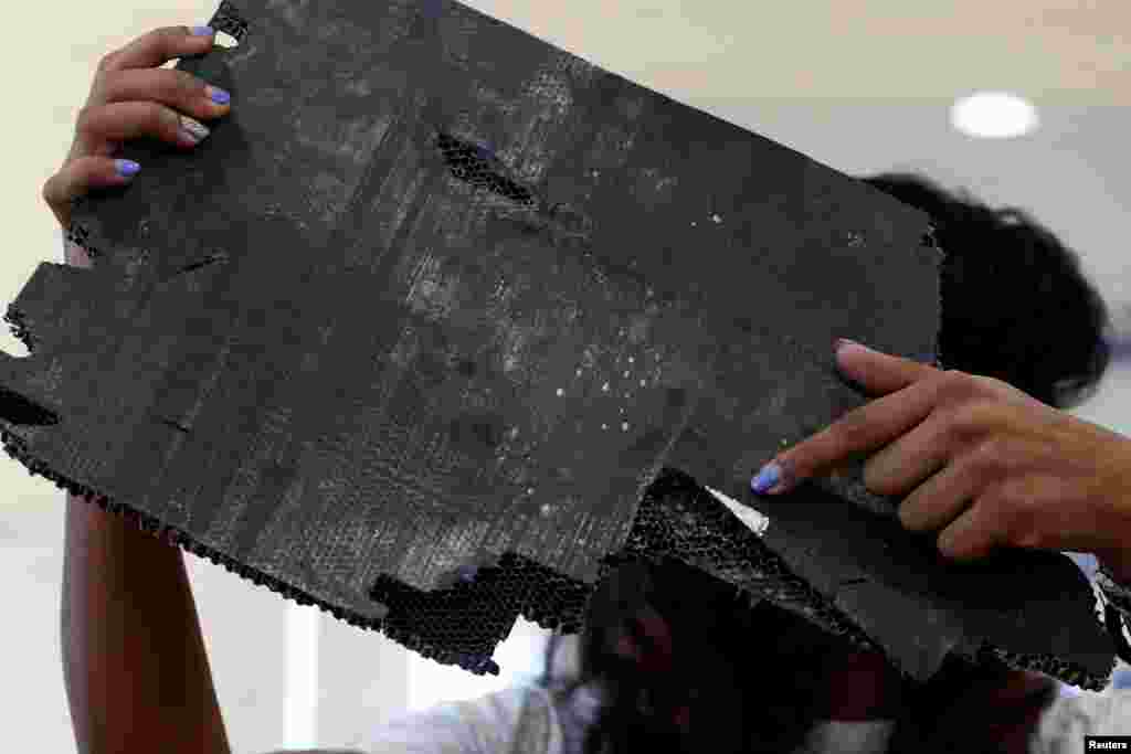 Grace Nathan, whose mother was onboard the missing Malaysia Airlines flight MH370, displays debris believed to belong to MH370 before handing over to Malaysia's Transport Minister Anthony Loke Siew Fook in Putrajaya, Malaysia.