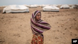 In this May 19, 2015 photo, Ashwaq stands outside her family's tent, at the Markaze refugee camp in Obock, northern Djibouti. Fleeing the war at home, thousands of Yemenis have made it across the Gulf of Aden to find refuge in Djibouti.