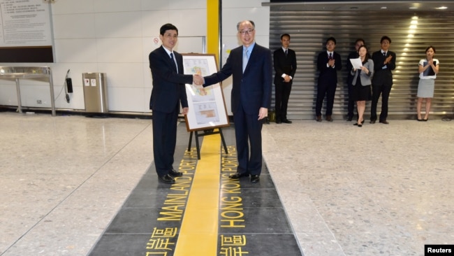 在香港西九龙高铁总站交接仪式上香港运输及房屋局局长陈帆（右）与中国深圳市人民政府的官员握手。（2018年9月3日）
