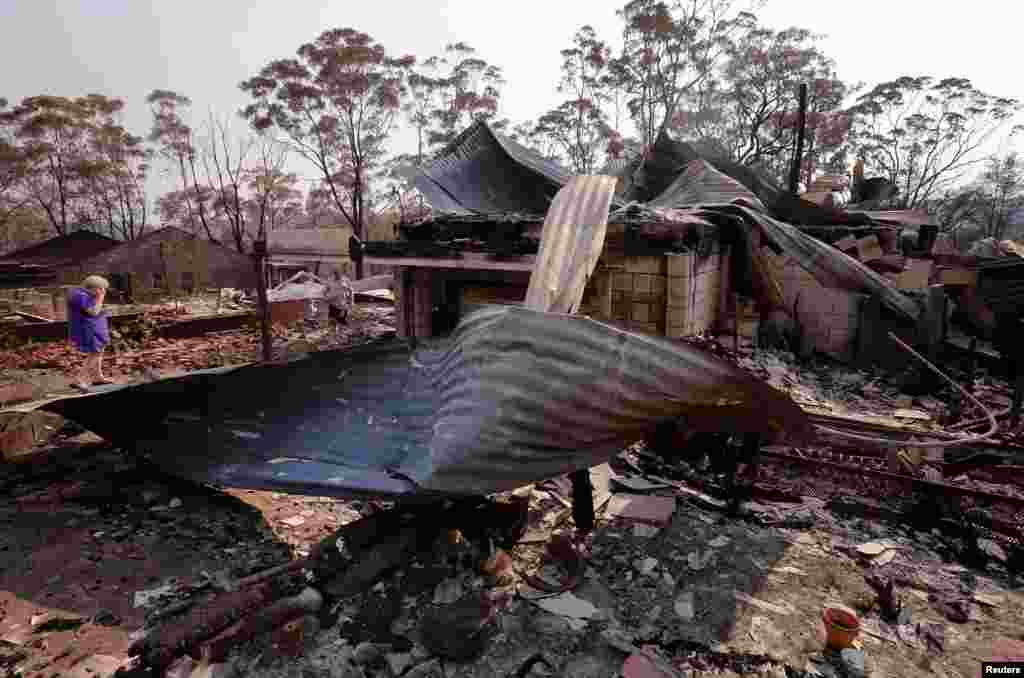 Delia Smith reacts as she inspects her family's house with her husband Colin after it was destroyed by a fire in the Blue Mountains suburb of Winmalee, west of Sydney, Australia, Oct. 21, 2013.