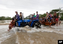 Commuters ride a farm tractor as it maneuvers through strong floodwaters along a highway in La Paz township, Tarlac province in northern Philippines, October 20, 2015.