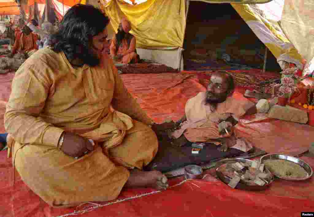 Mahadev Bharti (right), a Sadhu or a Hindu holy man, who said he stands at 18-inch (46 cm), speaks with a fellow Sadhu inside a tent on the banks of the river Ganges during the ongoing 'Kumbh Mela', or Pitcher Festival, in the northern Indian city of Allahabad.