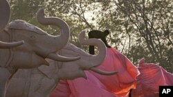 An Indian worker covers an elephant statue at Ambedkar Park in Noida, on the outskirts of New Delhi, India. Workmen using truckloads of cloth raced to comply with election officials who ordered the statues of Chief Minister of Uttar Pradesh state Mayawati