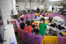 FILE - Unaccompanied migrant minors, aged 3 to 9, watch television inside a playpen at the U.S. Customs and Border Protection facility, the main detention center for unaccompanied children in the Rio Grande Valley, in Donna, Texas, March 30, 2021.