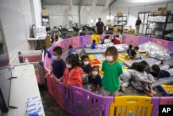 FILE - Unaccompanied migrant minors, aged 3 to 9, watch television inside a playpen at the U.S. Customs and Border Protection facility, the main detention center for unaccompanied children in the Rio Grande Valley, in Donna, Texas, March 30, 2021.