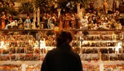 Seorang perempuan melihat patung-patung Natal yang dipajang di stan di pasar Natal tradisional di pusat kota Roma. (Foto: REUTERS/Tony Gentile)