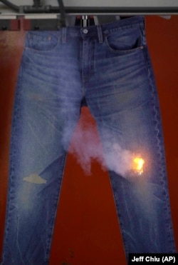 In this Feb. 9, 2018 photo, a machine marks wear patterns and damage on a pair of jeans with a CO2 laser at Levi's innovation lab in San Francisco.