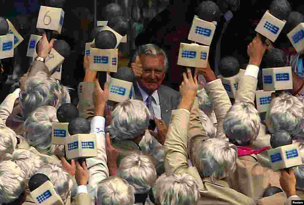 Former Australian prime minister Bob Hawke (C) reacts after drinking a beer, watched by members of the crowd dressed as cricket commentator Richie Benaud, during the second day of the fifth Ashes cricket test between England and Australia at the Sydney cricket ground, Jan. 4, 2014.