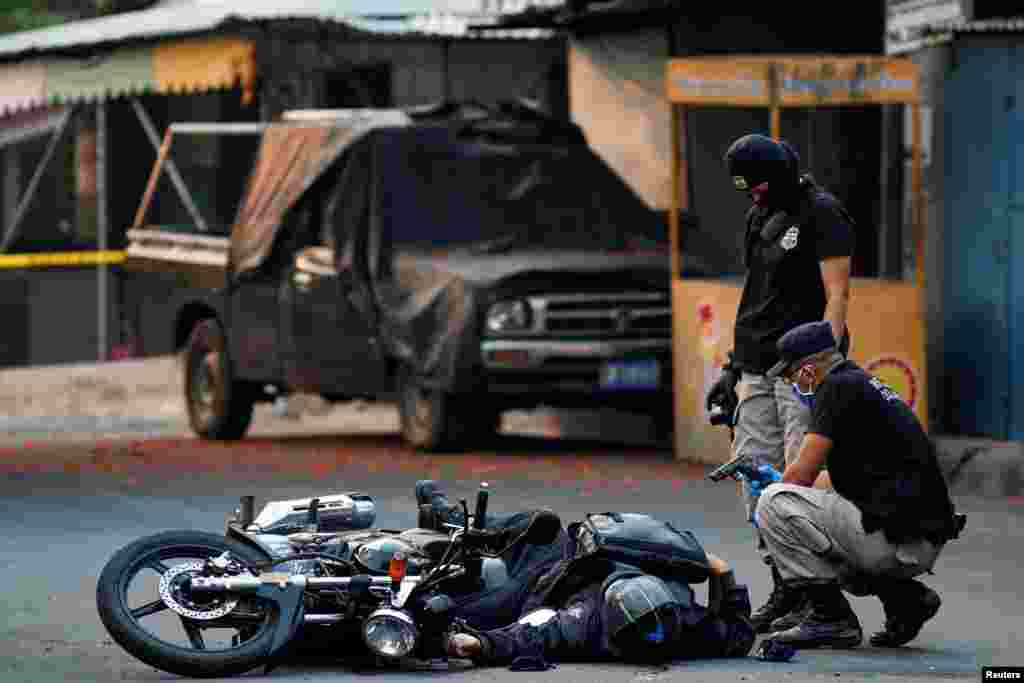 Agentes de la policía inspeccionan el lugar donde fue asesinado un agente de seguridad privado en la ciudad de San Martín, El Salvador. El fallecido fue parte de los 51 muertos en hechos violentos el fin de semana en el país centroamericano.