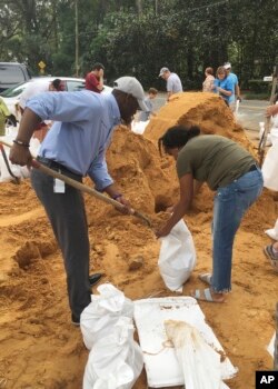 Andrew Gillum (izquierda), alcalde de Tallahassee y candidato a gobernador demócrata, ayuda a Eboni Sipling a llenar bolsas de arena en Tallahassee, Florida, el lunes 8 de octubre de 2018.