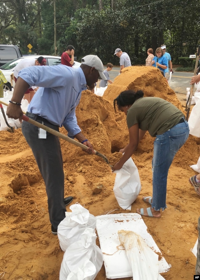 Andrew Gillum (izquierda), alcalde de Tallahassee y candidato a gobernador demócrata, ayuda a Eboni Sipling a llenar bolsas de arena en Tallahassee, Florida, el lunes 8 de octubre de 2018.