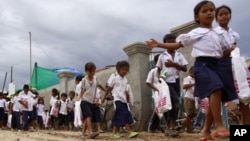 Cambodian schoolchildren walk on a muddy road near the dam site of Steung Mean Chey after they participated in an Intentional Children's Day event in the outskirts of Phnom Penh, file photo. 