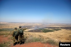 FILE - Israeli soldiers look at the Syrian side of the Israel-Syria border on the Israeli-occupied Golan Heights, Israel, July 7, 2018.