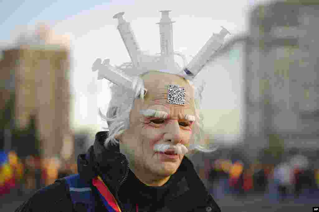 An anti-COVID-19 green pass protester wears a latex mask with syringes attached to it during a rally in front of the Victoria Palace, the government headquarters, in Bucharest, Romania.