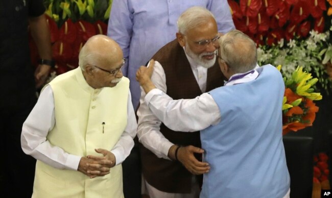 Indian Prime Minister Narendra Modi, second right, hugs senior Bharatiya Janata Party leader M.M. Joshi as L.K. Advani, left, watches after Modi's election as ruling alliance leader, in New Delhi, May 25, 2019.