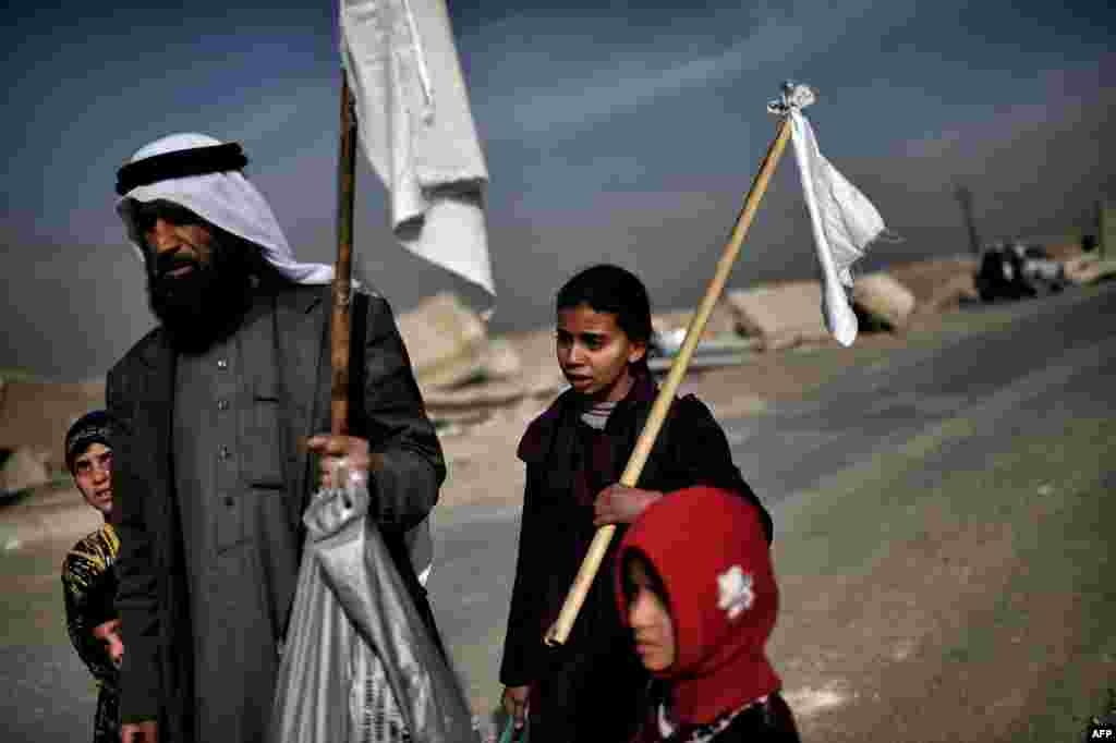 Iraqis holding white flags walk down a road as they flee Mosul during an offensive by security forces to retake the western parts of the city from Islamic State (IS) group fighters.
