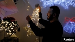 A Palestinian man arranges decoration lights in a shop in preparation for Christmas season, amid the coronavirus disease (COVID-19) outbreak, in Beit Sahour in the Israeli-occupied West Bank November 26, 2020. (REUTERS/Mussa Qawasma)