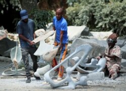 Zimbabwean sculptor Dominic Benhura carries a finished piece at his studio in Harare, Zimbabwe, March 2, 2020. (REUTERS/Philimon Bulawayo)