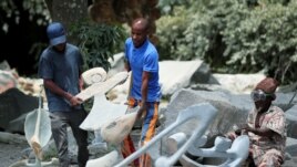 Zimbabwean sculptor Dominic Benhura carries a finished piece at his studio in Harare, Zimbabwe, March 2, 2020. (REUTERS/Philimon Bulawayo)