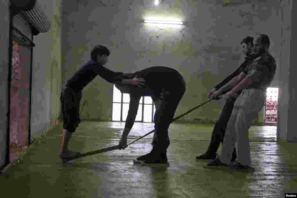 Men pull as a boy stands on a soap cutter in a soap factory in Idlib province, Syria, Jan. 30, 2016.