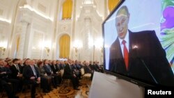 Russian President Vladimir Putin is seen on a screen during his annual state of the nation address at the Kremlin in Moscow, Russia, December 1, 2016. 